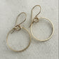 Silver hoop earrings on a textured beige fabric background