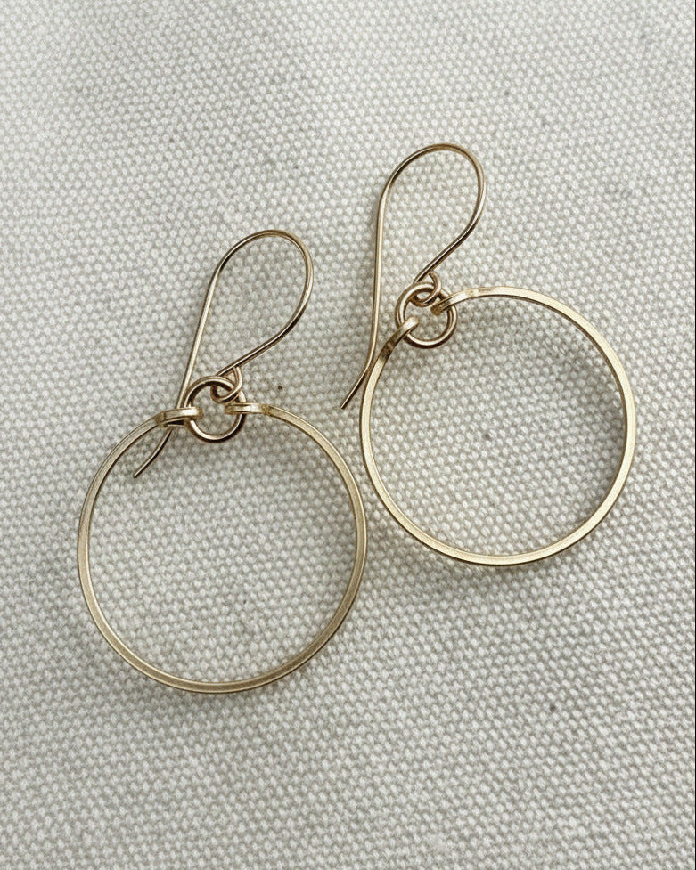 Silver hoop earrings on a textured beige fabric background