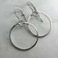 Pair of silver circle earrings on a light gray surface