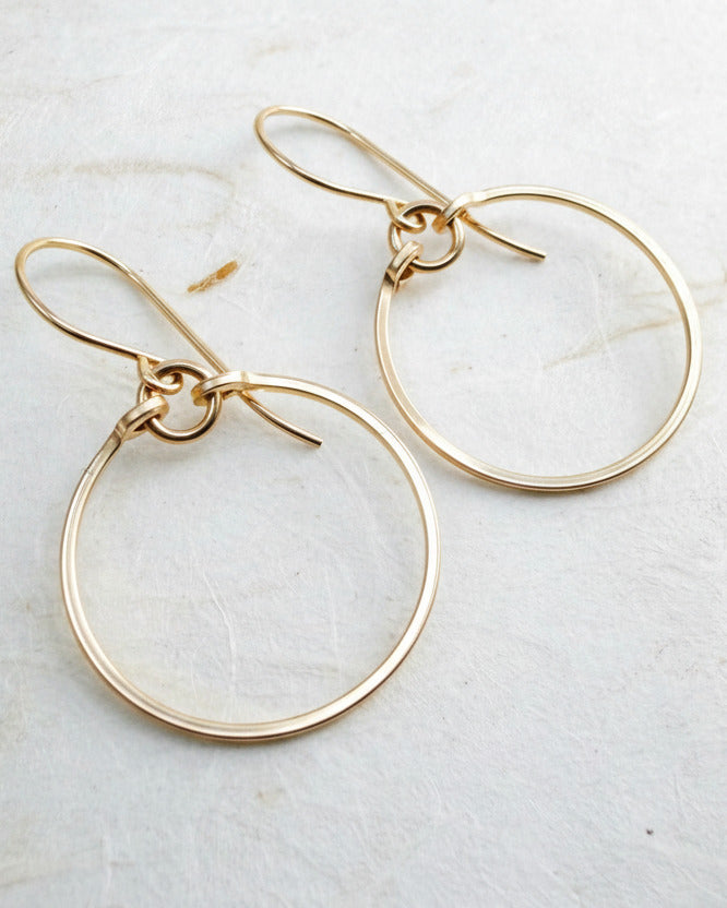 Gold hoop earrings on a light gray surface
