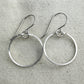 Pair of silver circle earrings on a textured  fabric background