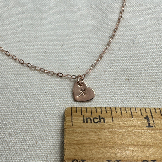 Necklace with a heart pendant next to a wooden ruler on a textured surface