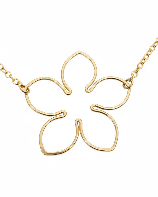 A delicate gold chain necklace featuring a minimalist, openwork five-petal flower pendant, displayed on a textured off-white surface.