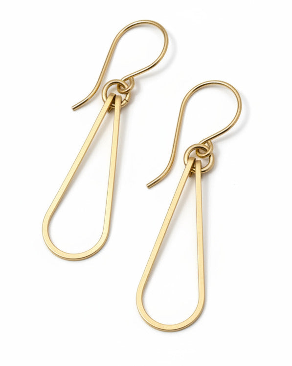 Pair of gold teardrop earrings on a gray fabric background