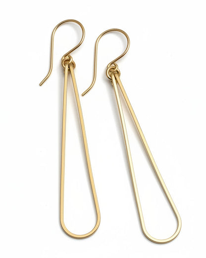 Pair of gold earrings on a light gray surface