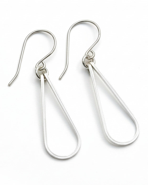 Pair of silver teardrop earrings on a gray background
