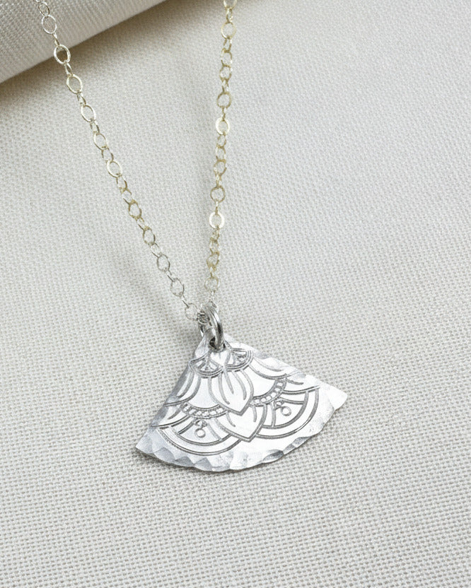 silver necklace with a half-circle pendant on a light fabric background