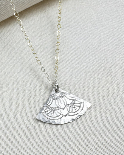 silver necklace with a half-circle pendant on a light fabric background