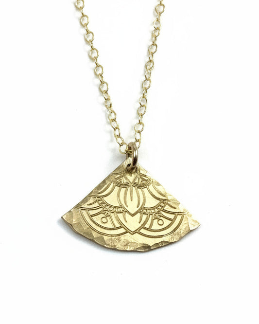 Gold necklace with a decorative pendant on a light gray background