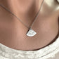silver necklace with a unique pendant worn by a person against a neutral background