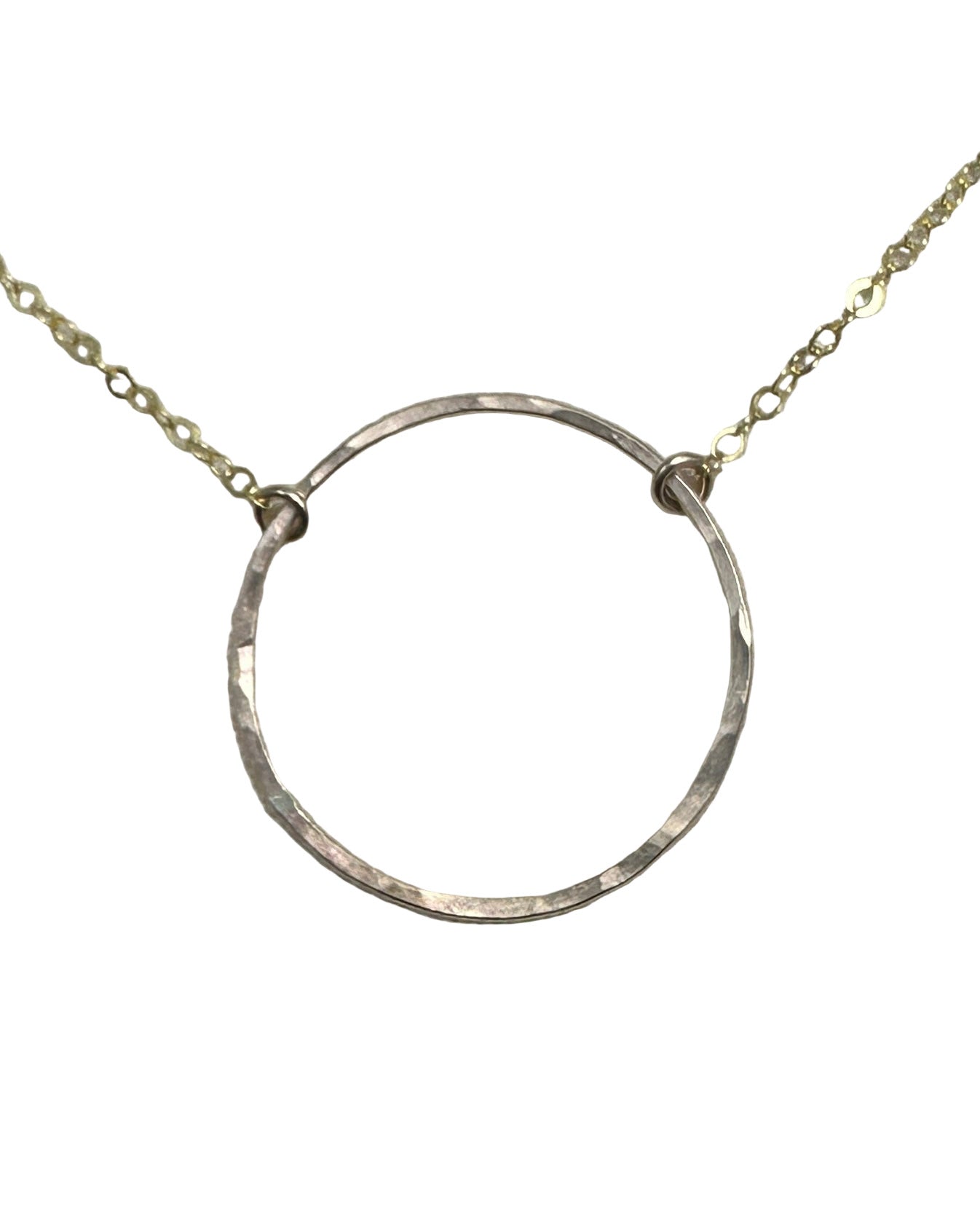 Silver circular pendant on a chain against a gray background