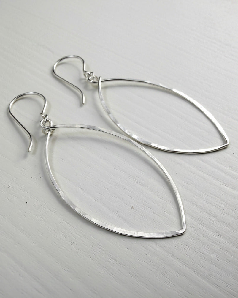 Pair of silver teardrop earrings on a light gray background