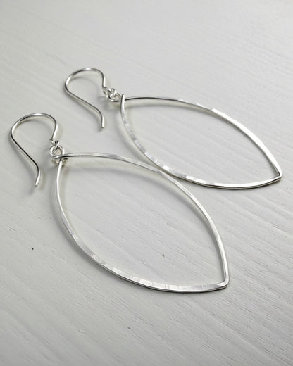 Pair of silver teardrop earrings on a light gray background