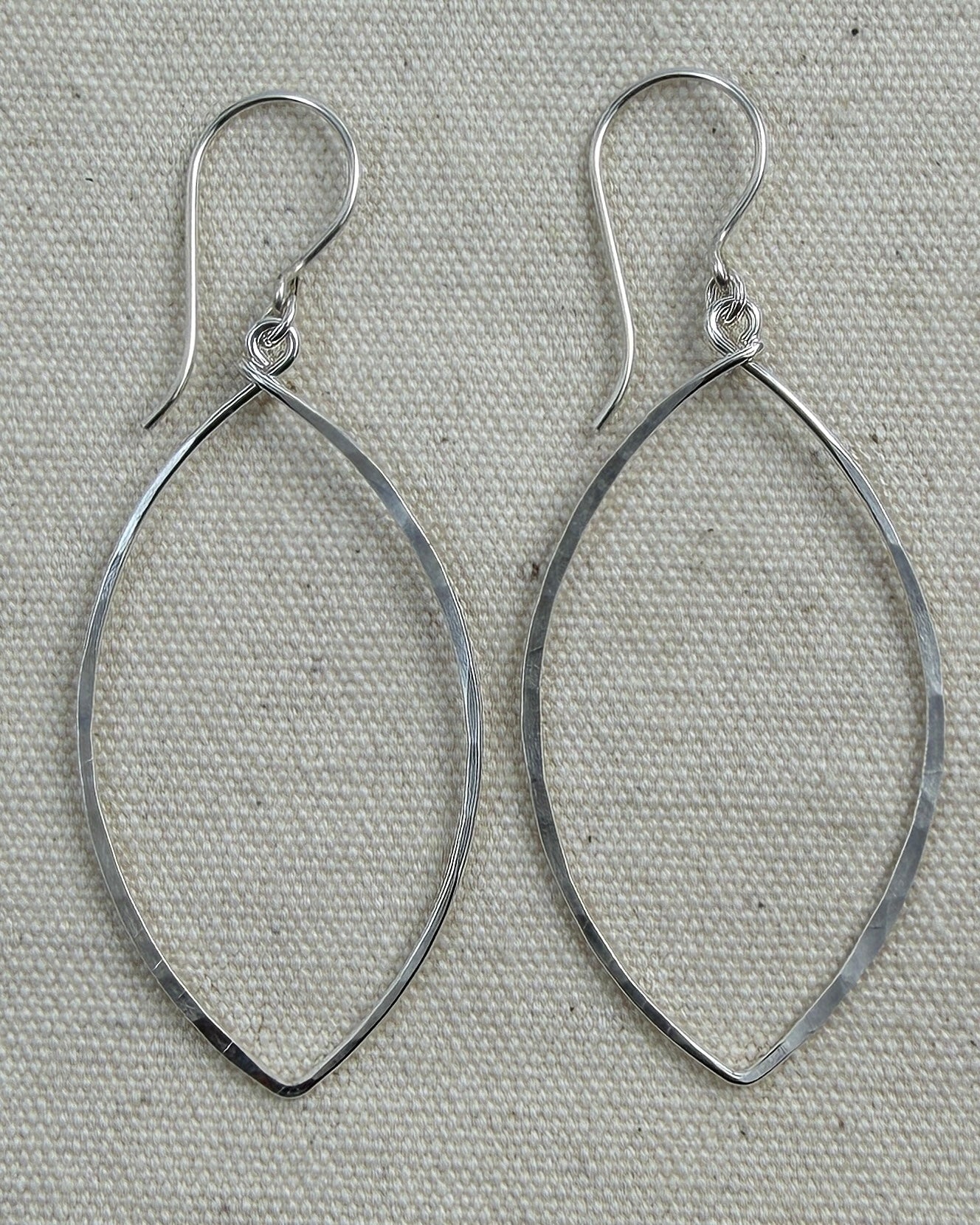 Pair of silver hoop earrings on a textured gray background