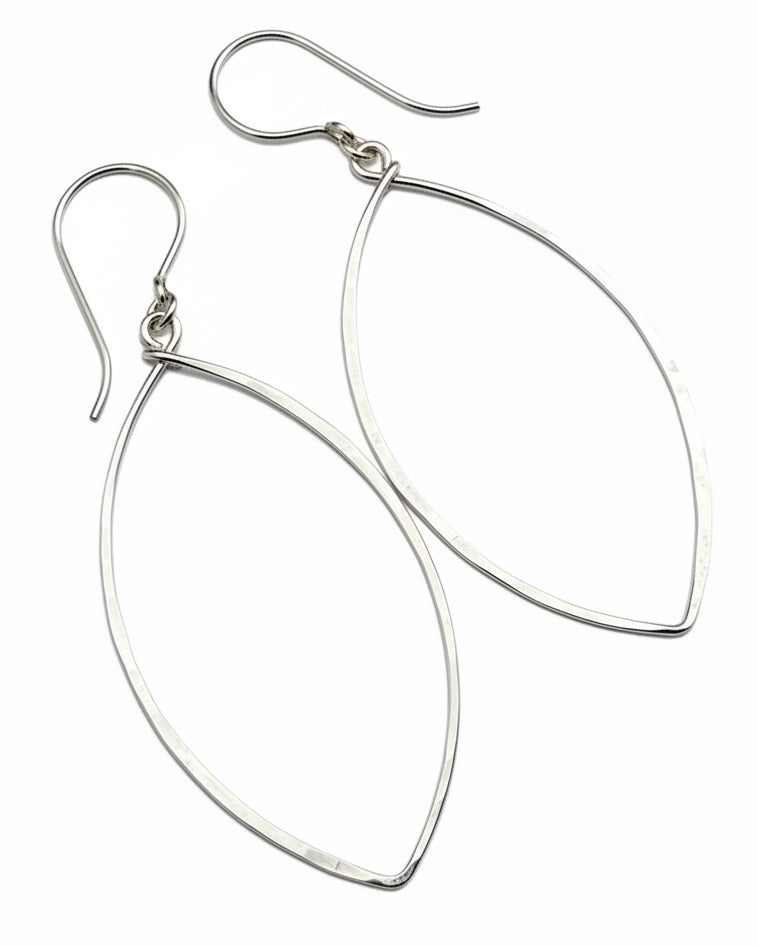 Silver teardrop earrings on a textured gray surface