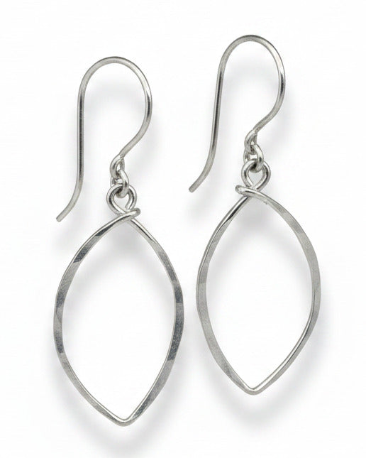 Pair of silver earrings on a textured beige background