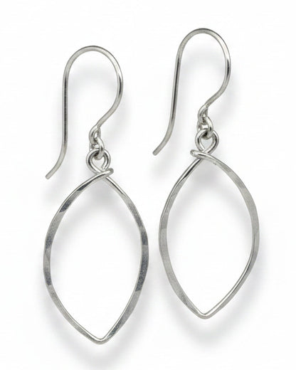 Pair of silver earrings on a textured beige background